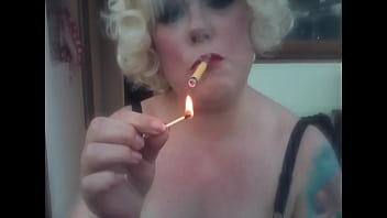 Une Maîtresse Rétro Blonde Fumant Une Cigarette Sobranie Jaune Avec Une Lumière D'aLlumette